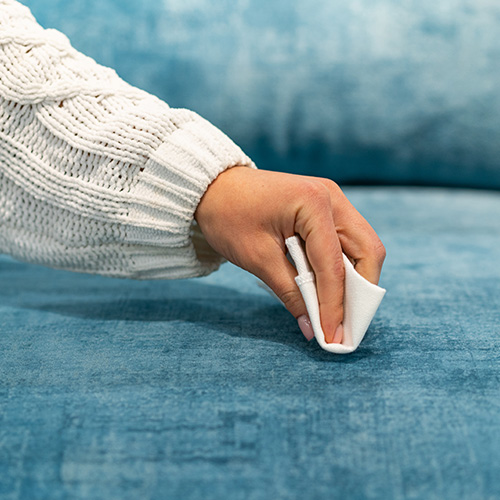 Ein blaues Samtsofa wird mit einem Tuch abgetupft